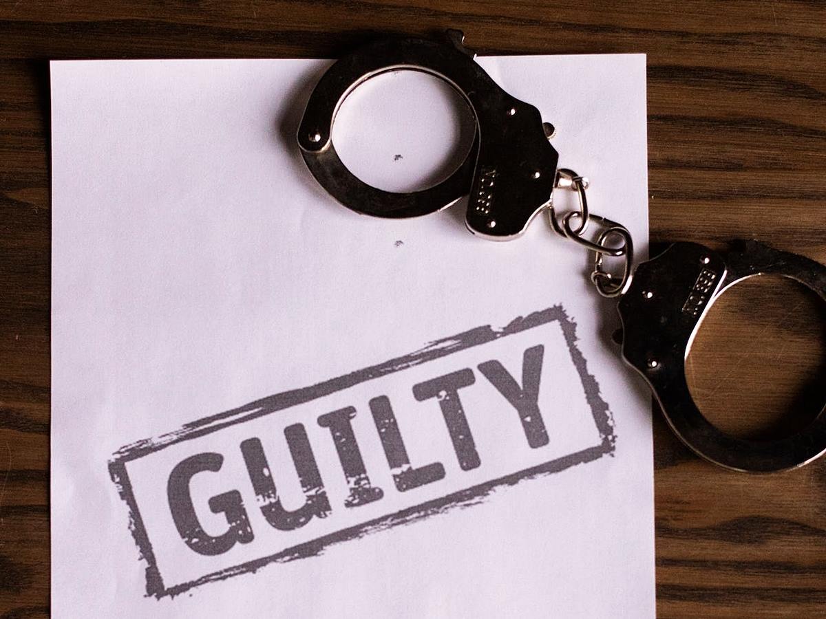 Stainless steel handcuffs on paper stamped with 'GUILTY' in gray