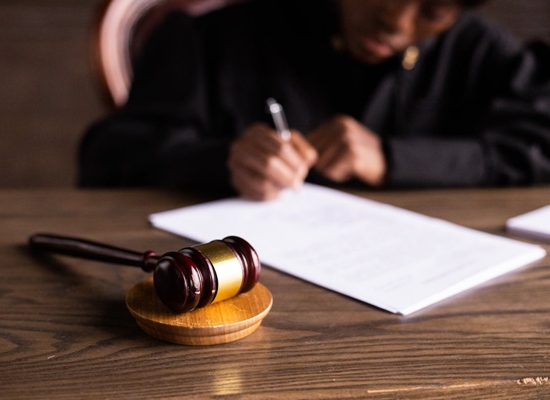 Judge completing paperwork beside wooden gavel