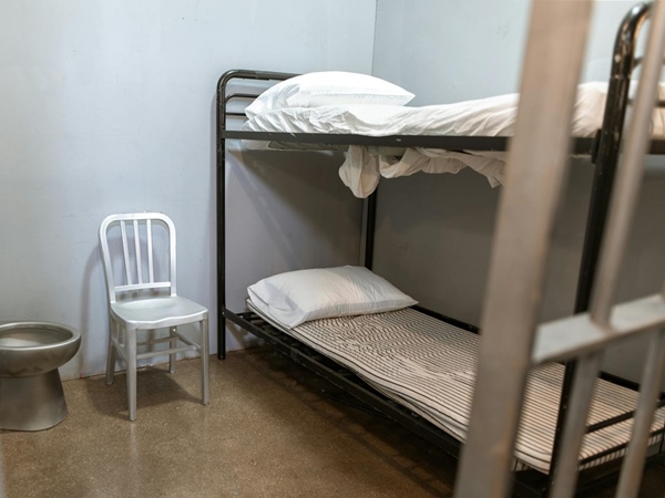 Jail cell with steel toilet, metal chair and twin-sized bunk beds