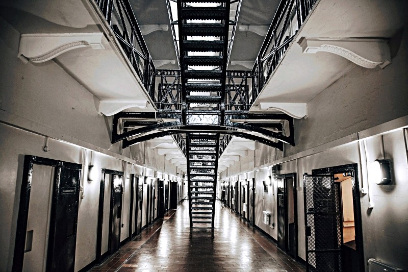 Detention center hallway with staircase and open jail cell doors