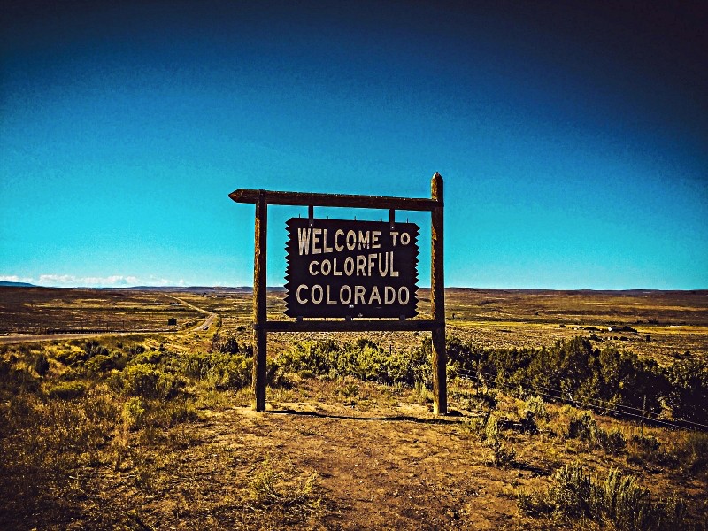 Wooden sign at Colorado border reading 'Welcome to Colorful Colorado'