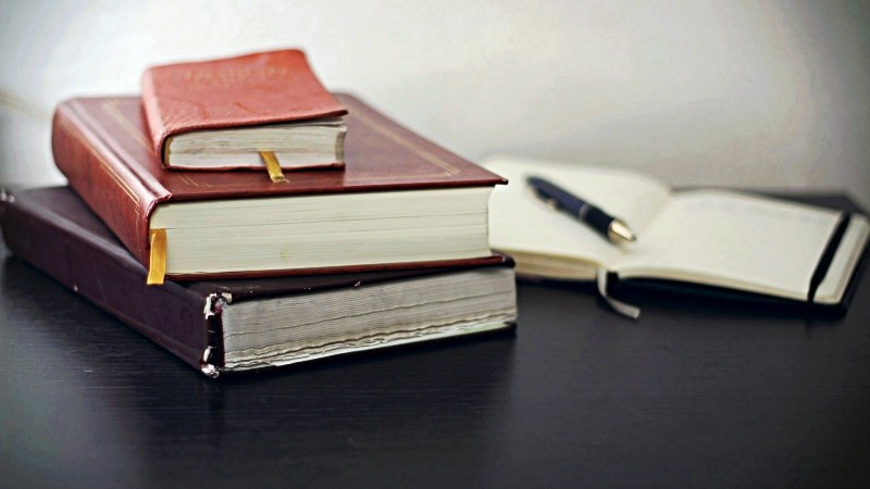 Stack of law books beside paperwork and fountain pen